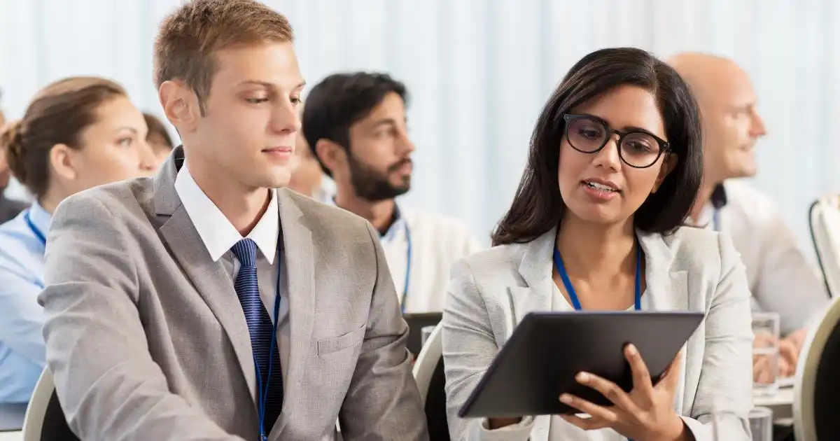 Professionals reviewing tablet during seminar